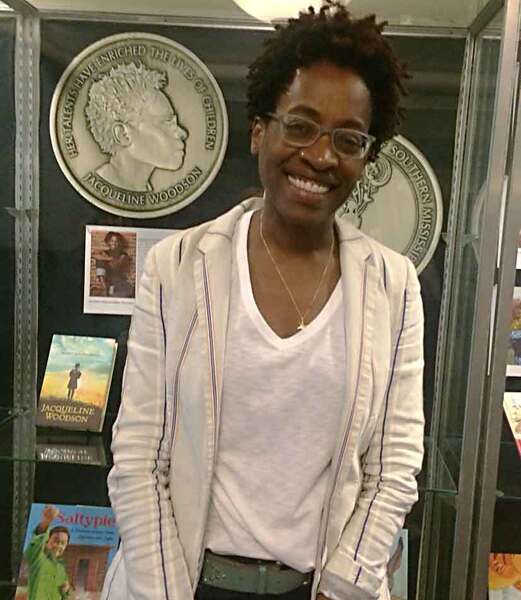 Jacqueline Woodson standing before a display of awards